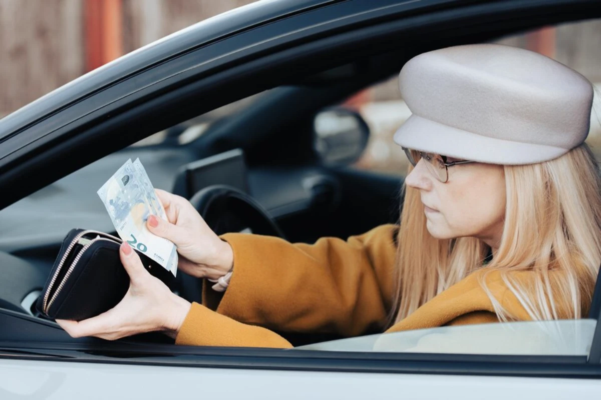 middleaged-woman-sits-wheel-car-looks-euro-wallet-pay-parking